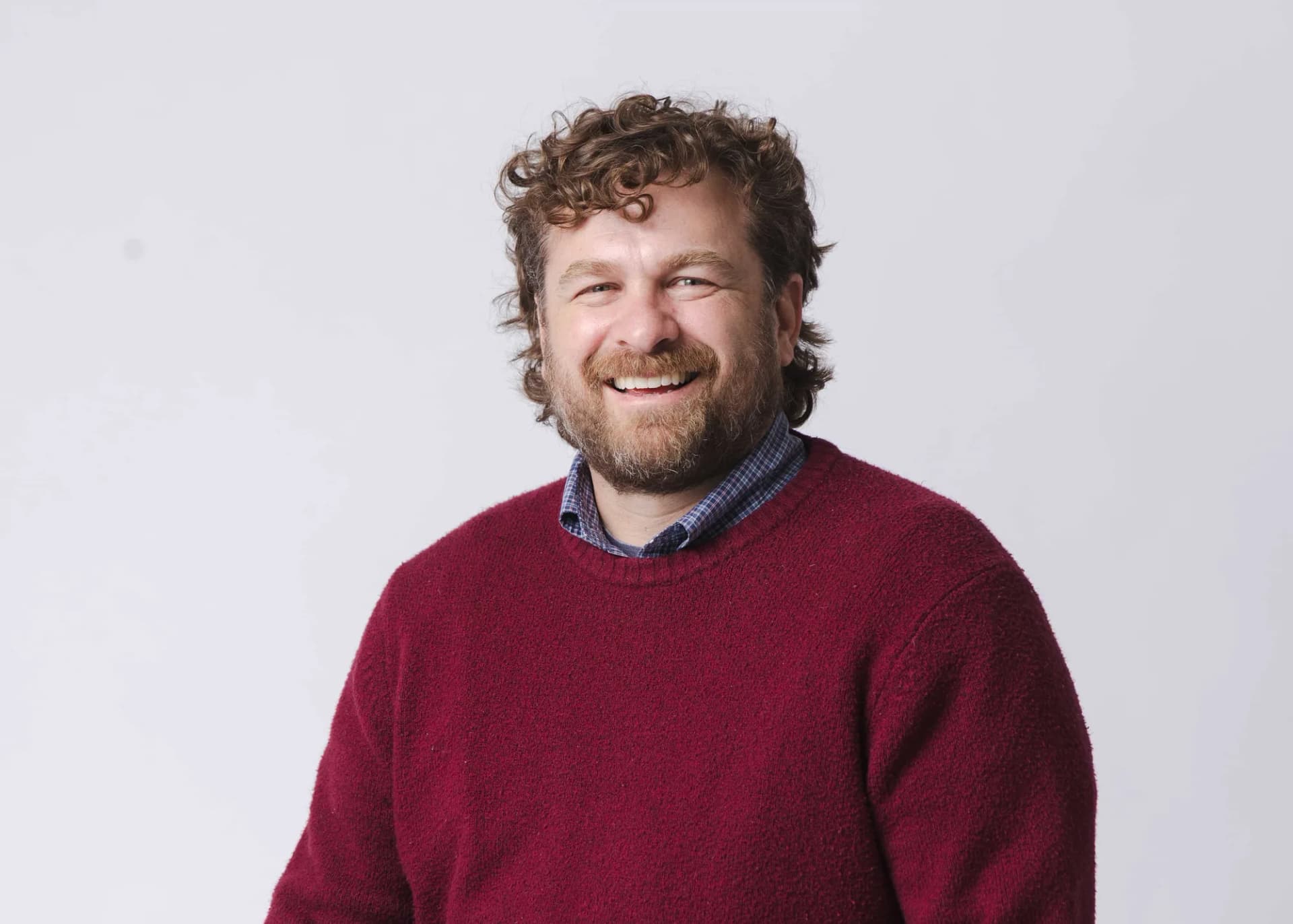 A studio portrait of Brannon in a red sweater against a plain pale background.